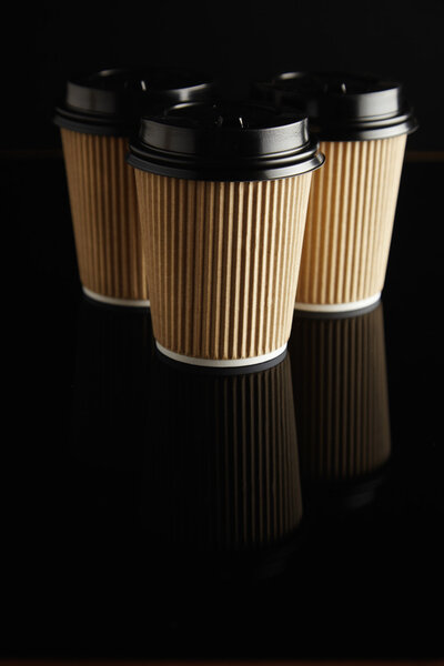 Brown takeaway coffee cups with black lids