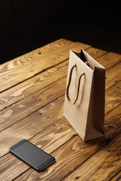 Sacchetto di carta artigianale in piedi su un tavolo di legno marrone rustico — Foto Stock