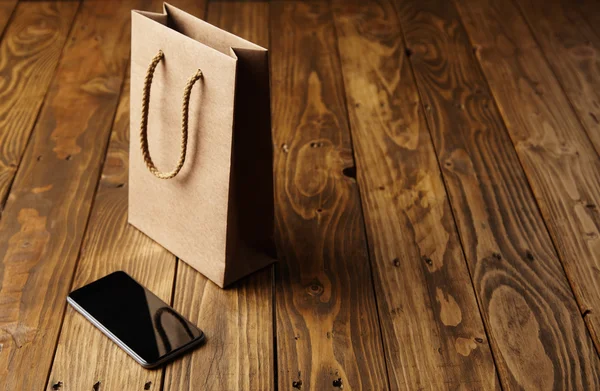 Bolso de papel artesanal que refleja en teléfono inteligente negro — Foto de Stock