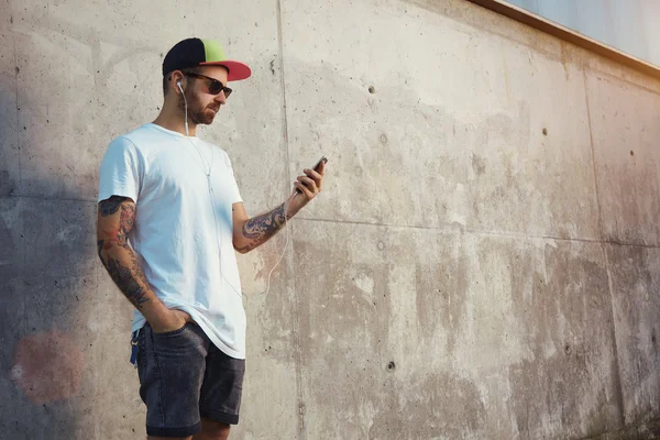 Tattooed man looking at his smartphones screen — Stock Photo, Image