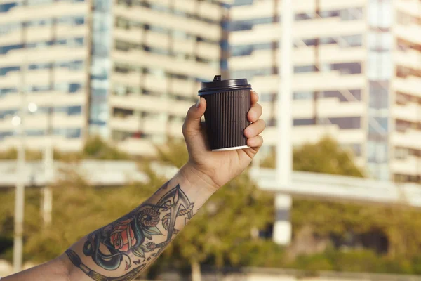 Blank paper coffee cup in tattooed mans hand — Stock Photo, Image