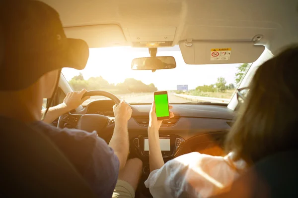 Man holds hands on wheel and girl shows smartphone — Stock Photo, Image