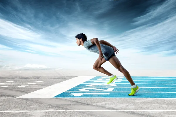 Sprinter no início da pista de corrida azul — Fotografia de Stock