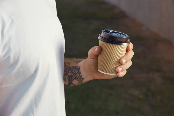 Татуированный мужчина с бумажной чашкой кофе — стоковое фото