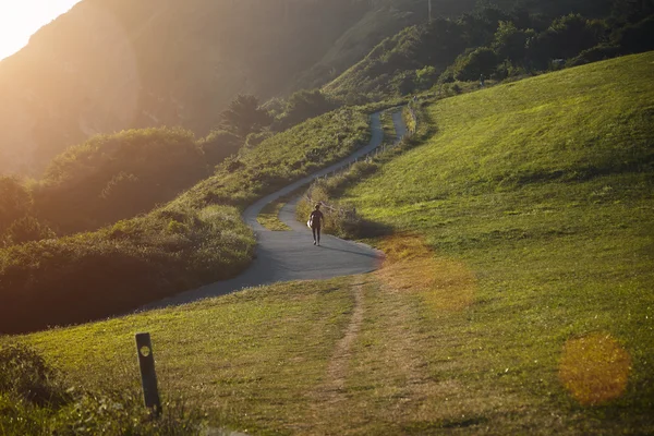 Surfista caminando colina arriba en la carretera sinuosa — Foto de Stock