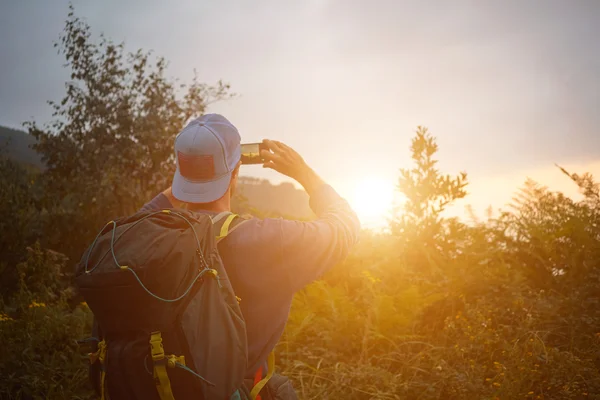 Reppumatkailija ottaa kuvan auringonlaskusta — kuvapankkivalokuva