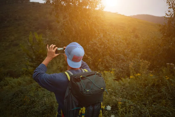 Рюкзак фотографує захід сонця на смартфоні — стокове фото