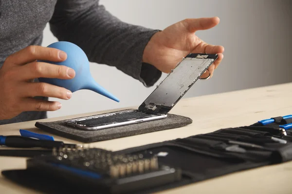 Člověk čištění chytrý telefon pomocí stříkačky — Stock fotografie