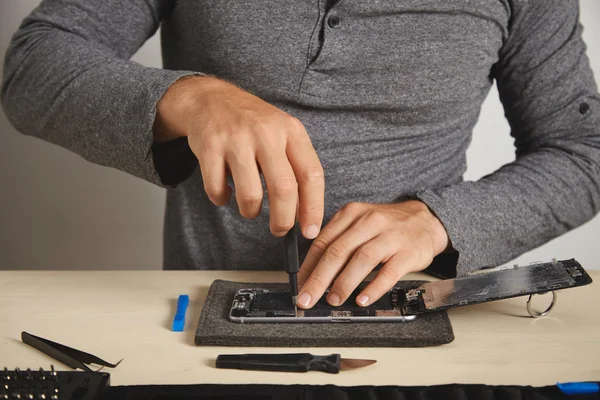 Master uses driver to unscrew screws in smartphone — Stock Photo, Image