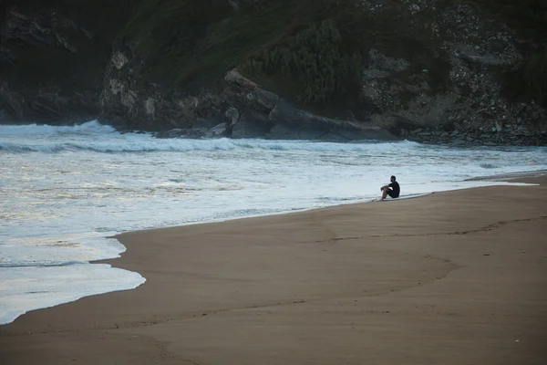 Surfer sitting at the edge of the beach looking  waves — Stock Photo, Image