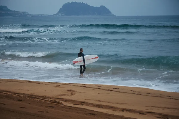 Surfista de fato de mergulho a entrar na água — Fotografia de Stock
