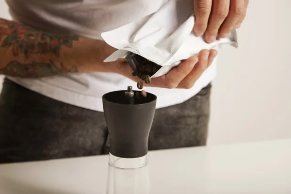 Man falling coffee beans into grinder — Stock Photo, Image