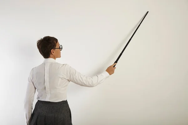 Insegnante che punta al muro bianco con puntatore — Foto Stock