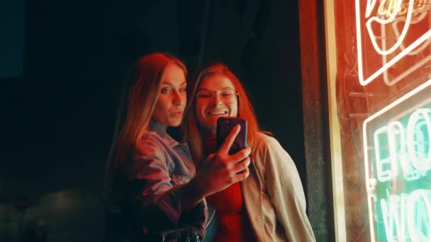 Dwa tysiąclecia kobiety pozować na aparat fotograficzny w neon — Wideo stockowe