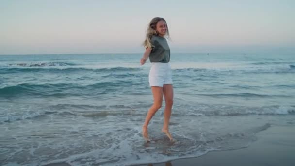 Νεαρή γυναίκα χορεύει ευτυχισμένη στην παραλία κύμα ακτή — Αρχείο Βίντεο