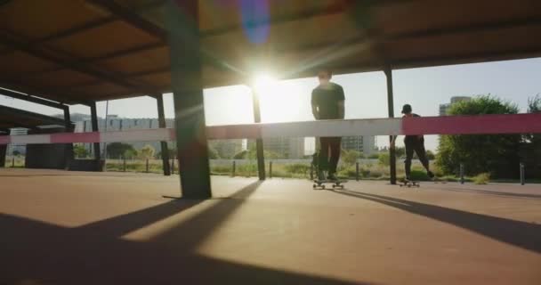 Два молодых парня ездят по городу на скейтбордах — стоковое видео