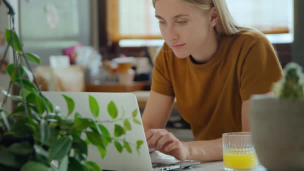 Ung kvinna arbetar på hemmakök på laptop — Stockvideo