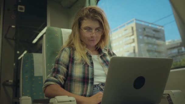 Νεαρή γυναίκα εργάζεται σε φορητό υπολογιστή κατά τη μετακίνηση με το τρένο — Αρχείο Βίντεο