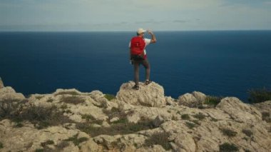 Sırt çantalı bir adam dağ yamacında yürüyüş yapıyor.