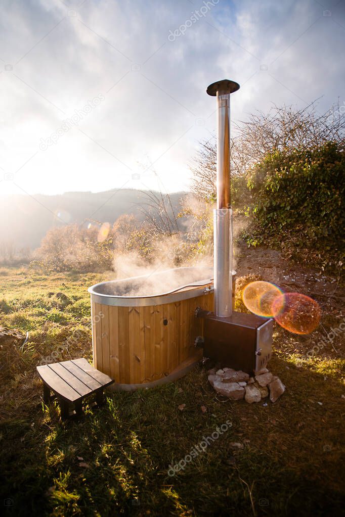 Steaming wooden hot tub in middle of field nature