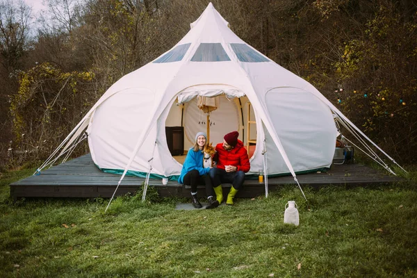 Couple sit in front of glamping tent outdoors — Stock Photo, Image