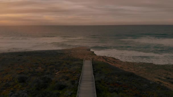 Cinematic epic sunset shot of boardwalk near sea — Stockvideo