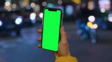 Gece elinde yeşil ekran telefonu tutan kadın.
