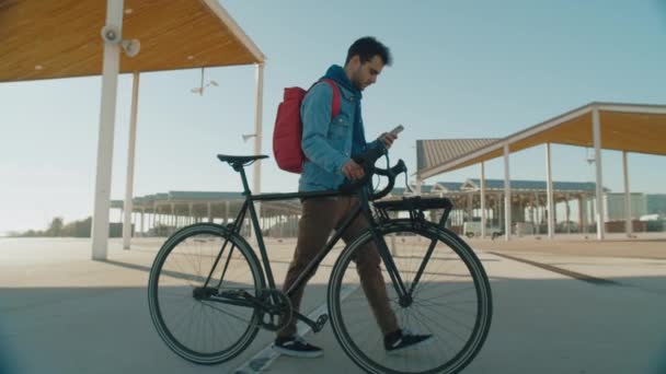Millennial youth walk with smartphone and bike — Vídeo de Stock