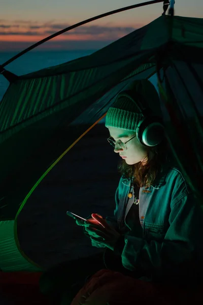 Giovane donna ascoltare musica o podcast in tenda — Foto Stock