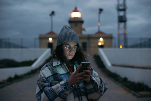 Genç bayan, alacakaranlıkta akıllı telefona bak. — Stok fotoğraf