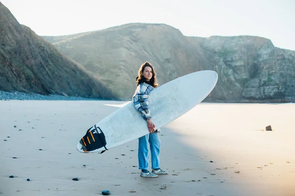 Giovane donna in spiaggia vestito casual con tavola da surf — Foto Stock