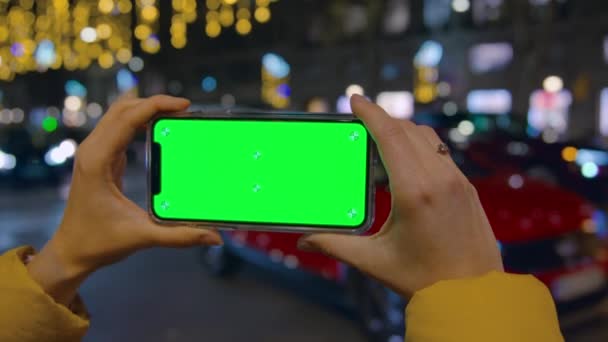 Persona mantenga el teléfono inteligente horizontalmente en la ciudad de noche — Vídeos de Stock