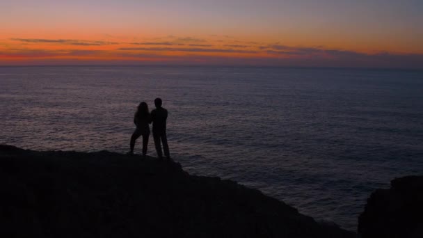 Σιλουέτα ζευγάρι με τα πόδια στην άκρη του γκρεμού στο ηλιοβασίλεμα — Αρχείο Βίντεο