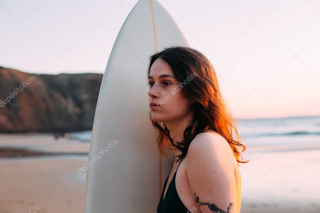 Young authentic woman with surfboard at beach