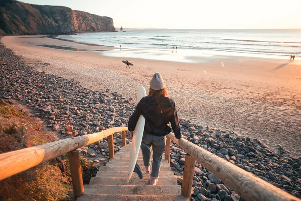 Junge Surferin geht bei Sonnenaufgang zum Strand — Stockfoto