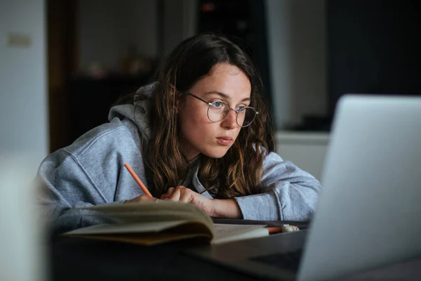 Young woman at home use laptop and write notes — Stock Photo, Image