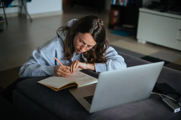 Young woman at home use laptop and write notes — Stock Photo, Image