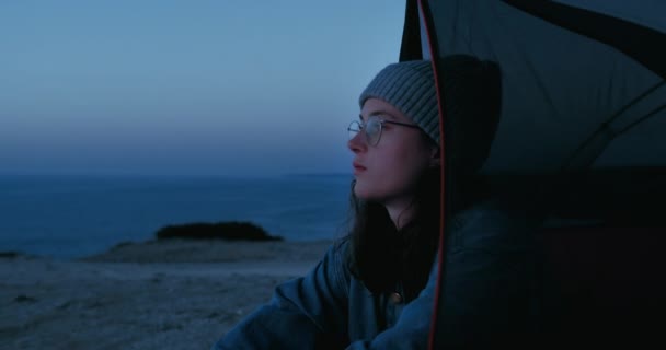 Genç bir kadının portresi kamp gezisinde gün batımını izliyor. — Stok video