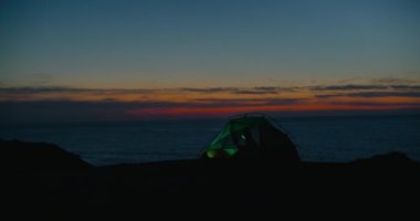 Yalnız genç bayan kamp çadırında telefona bakıyor.