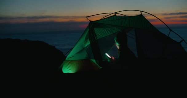 Lonely young woman look at phone in camping tent — Stock Video