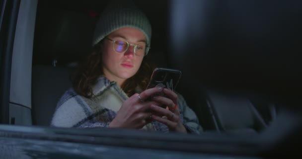 Mulher sente-se dentro do carro, tela iluminada rosto com telefone — Vídeo de Stock