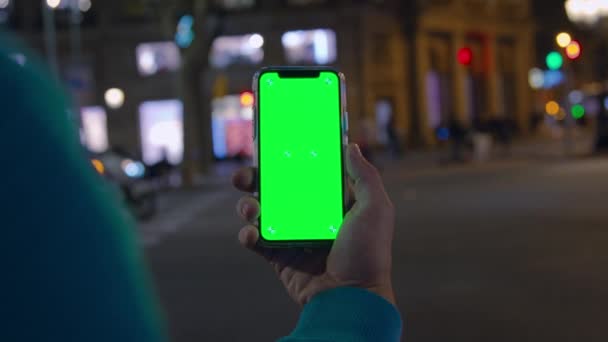 Persona mantenga el teléfono inteligente horizontalmente en la ciudad de noche — Vídeo de stock