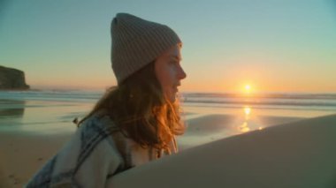 Plajda günlük kıyafet giymiş kadın sörfçü.