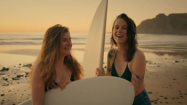 两名女冲浪者在日落海滩看着相机 — 图库视频影像