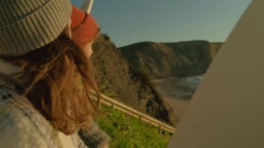 İki sörfçü kadın sahilde dalgalar hakkında konuşuyor.