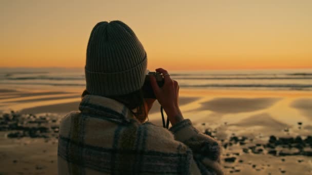 Молодая женщина фотографирует эпический пляжный закат — стоковое видео