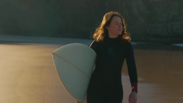 Authentiek shot van surfer wandeling op zonsopgang strand — Stockvideo