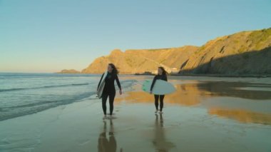 İki bayan sörfçü destansı plajda takılıyor.