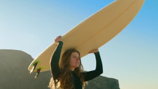 Mujer joven surfista llevar tabla de surf en la playa — Vídeos de Stock