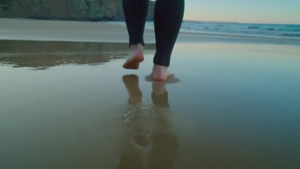 Kamera begleitet barfüßigen Surfer im Neoprenanzug am Strand — Stockvideo